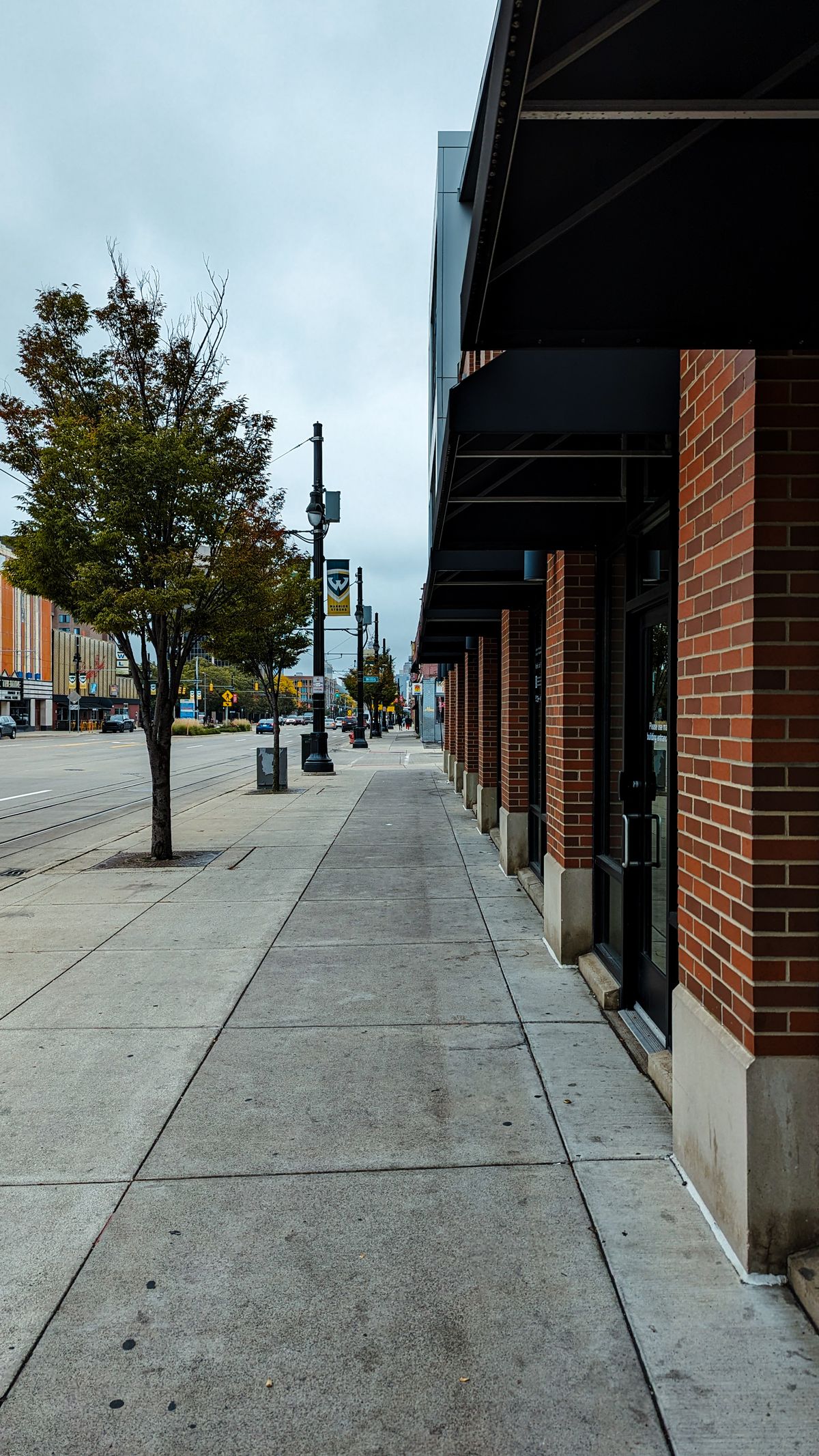 Concrete sidewalk running past brick storefronts in a commercial district
